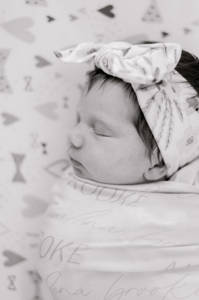 Black and white close up of baby girl swaddled in personalized blanket