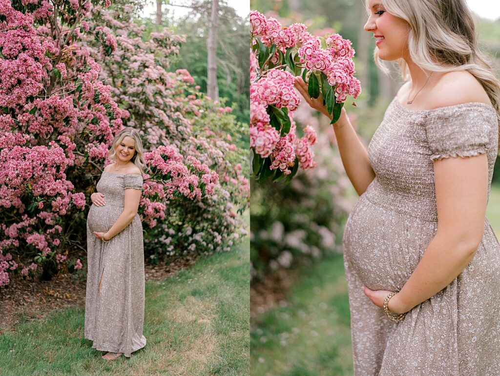 An expecting mother in a brown and tan floral dress holding her pregnant belly while standing under a pink flowering bush at Schoepfle Gardens by maternity photographer Brittany Serowski Photography.