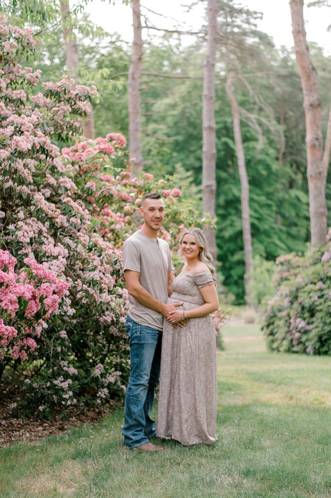 A mother and father expecting their second child. holding mom's pregnant belly at Schoepfle Gardens in brown and tan, neutral clothing by maternity photographer Brittany Serowski Photography.