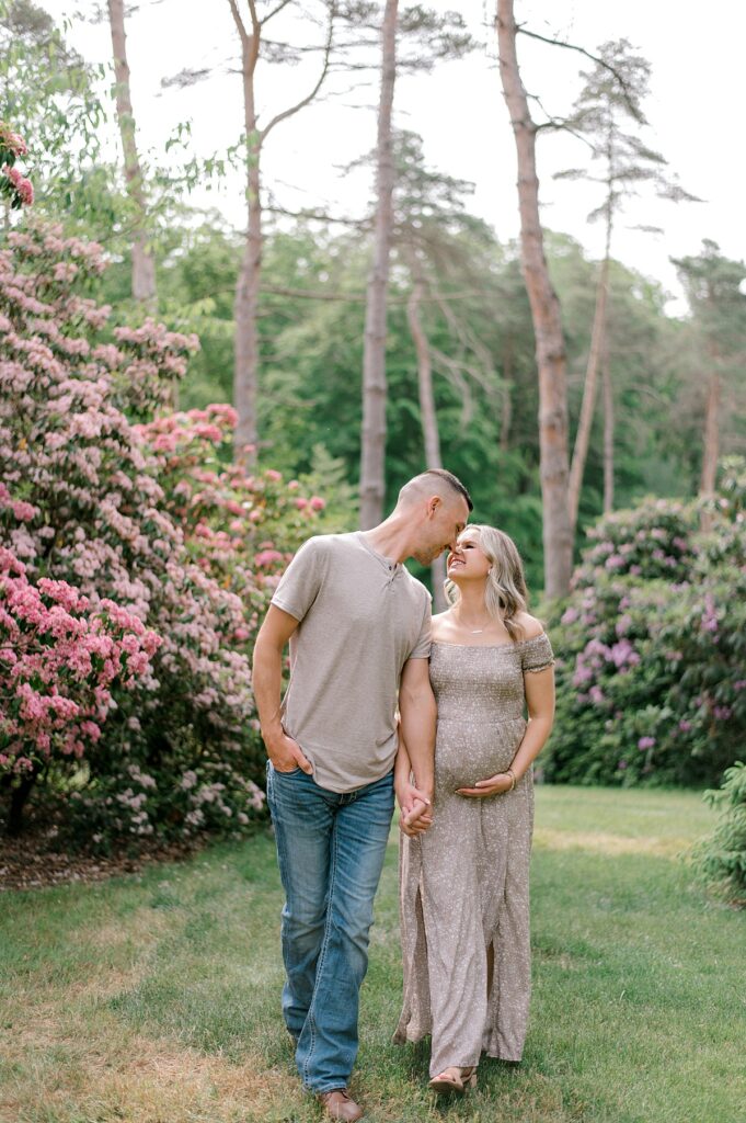 An expecting mother and husband holding hands and walking through the gardens in Schoepfle Gardens by maternity photographer Brittany Serowski Photography.