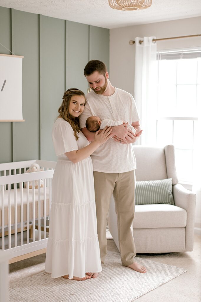 A Medina neutral nursery session by newborn photographer, Brittany Serowski Photography, with a new mother and father holding their newborn son in his neutral nursery in neutral clothing.