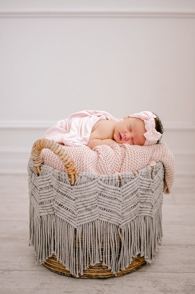 A infant girl sleeping in a basket with pink blankets inside at Lake Arts Studio by Cleveland Newborn Photographer, Brittany Serowski Photography.