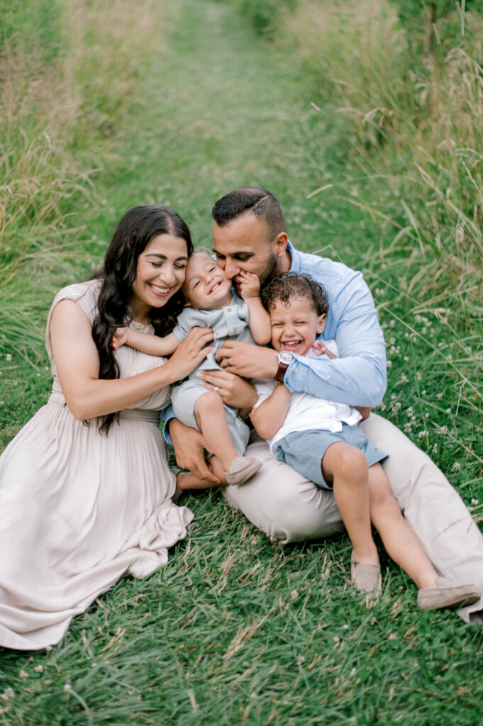 A family of four in cream and blue outfits sitting piled up together while mom and dad are tickling the kids by Brittany Serowski Photography for her Fall & Holiday Cleveland Minis.