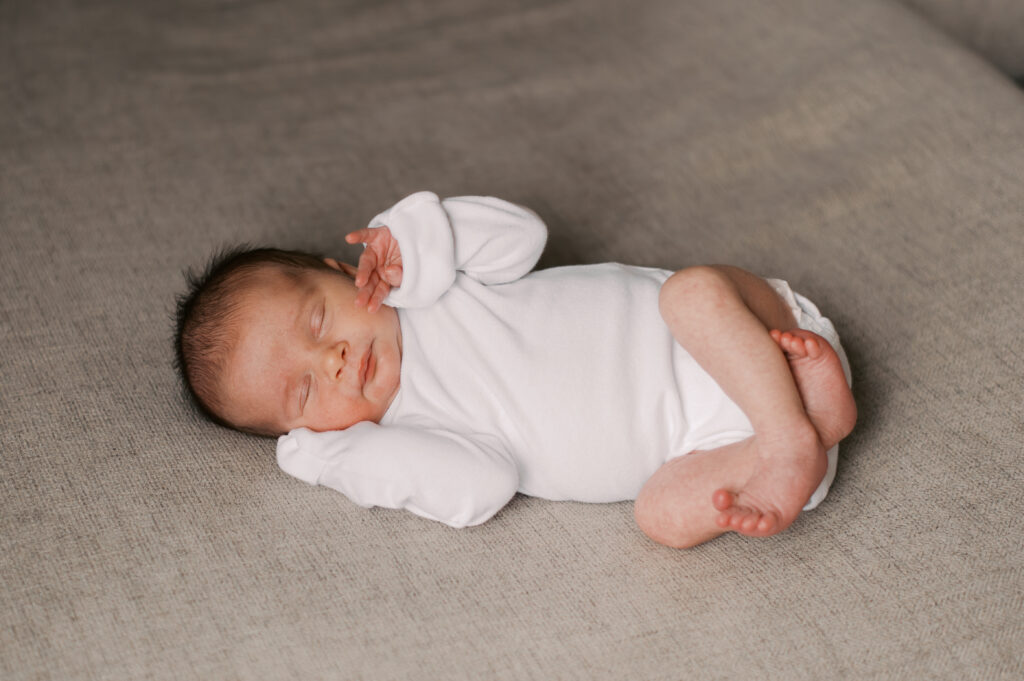Winter cleveland newborn photography session at home with baby in a white onesie on a neutral couch. Photographed by Brittany Serowski Photography.