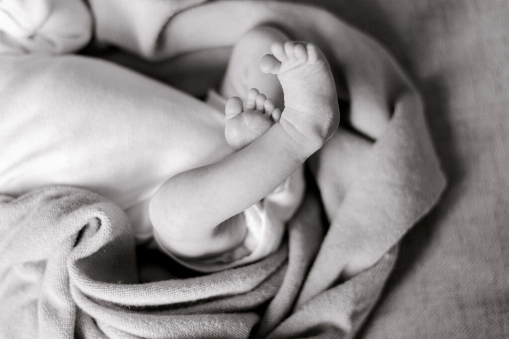 Cozy Cleveland in-home newborn portrait with winter light. A black and white photo of a newborn baby's toes. Captured by Brittany Serowski Photography.