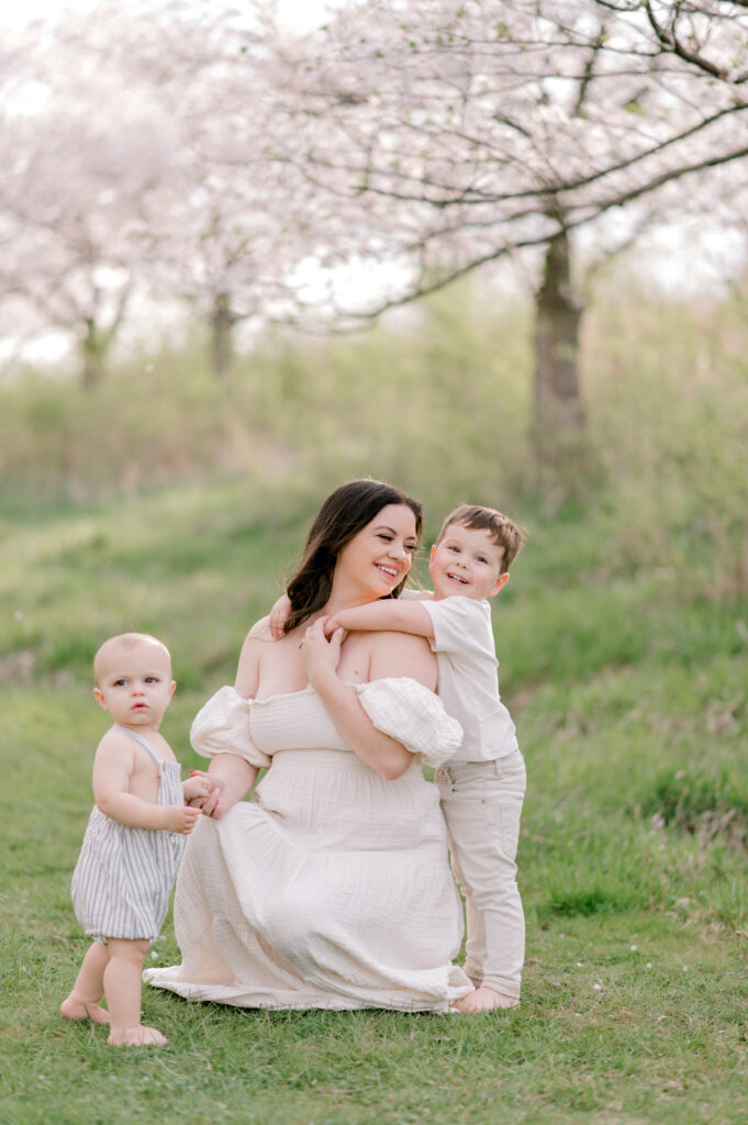 A mother with her two sons, sitting under the cherry blossom trees at Brookside Reservation in Cleveland, OH. Photographed by Spring Cleveland Photographer, Brittany Serowski Photography.