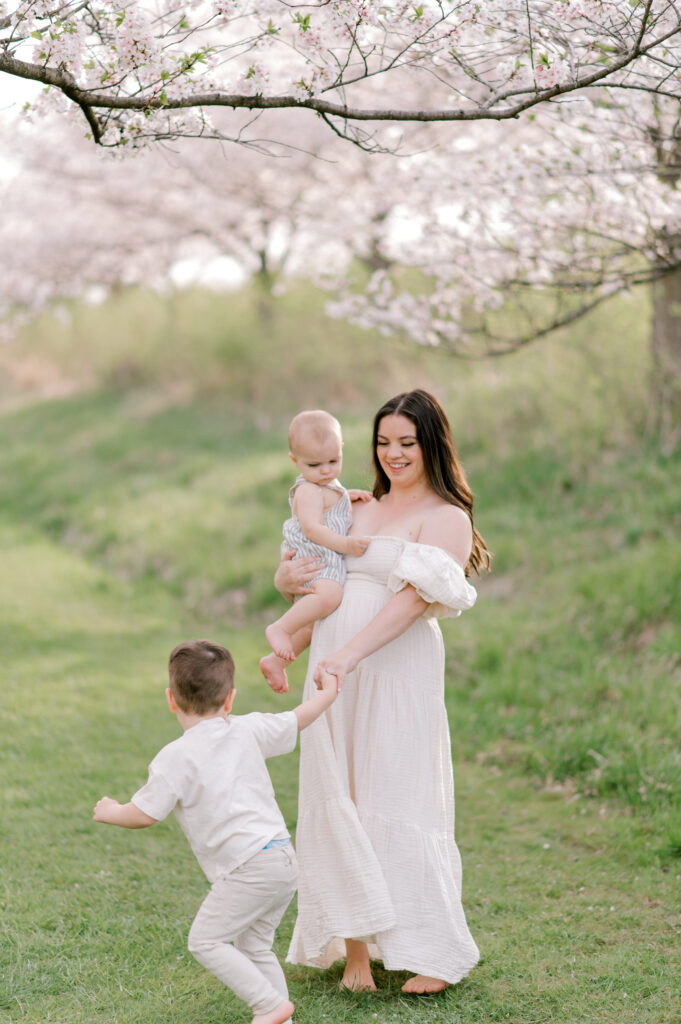 A mother and her two young sons, running under the cherry blossom trees in Brookside Reservation in Cleveland, OH. Captured by Cleveland Family Photographer, Brittany Serowski Photography.